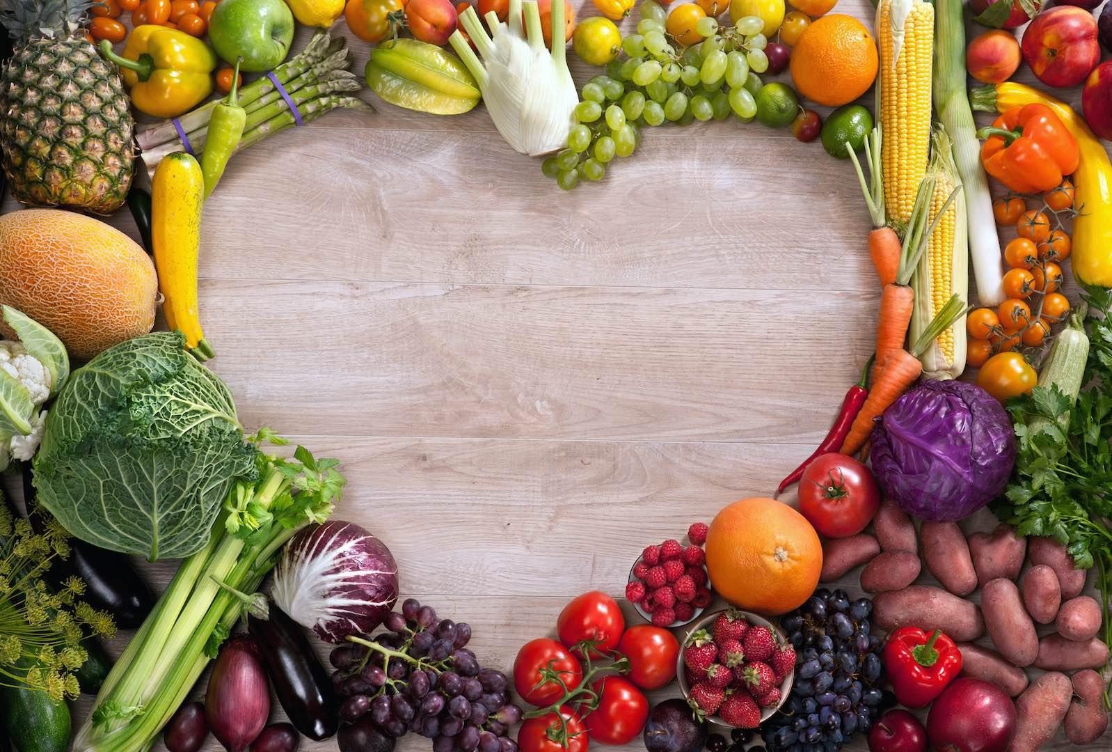 Fresh fruits and vegetables arranged in a circle on a wooden surface